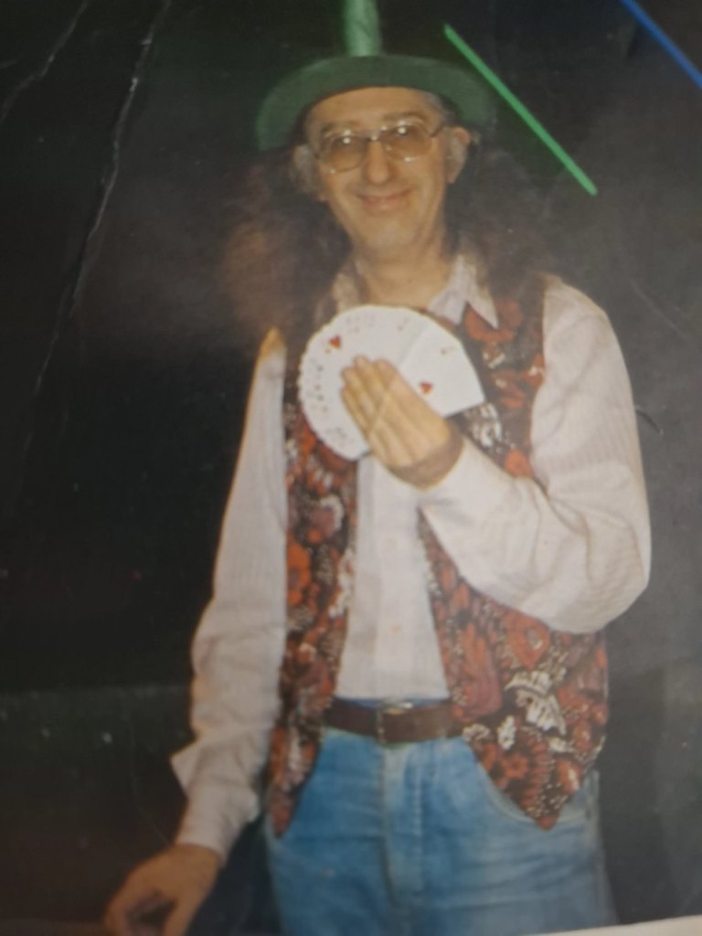 Juan Tamariz joven, con sombrero verde, chaleco de flores y un abanico de cartas en la mano